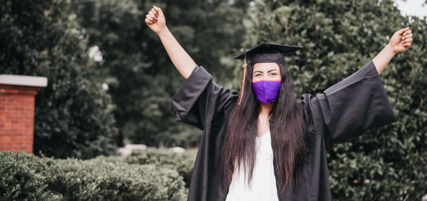 Clemson graduate celebrates wearing cap and gown with face mask on