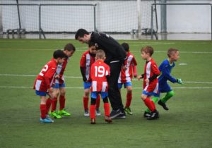 A soccer coach instructs his boys youth soccer team.