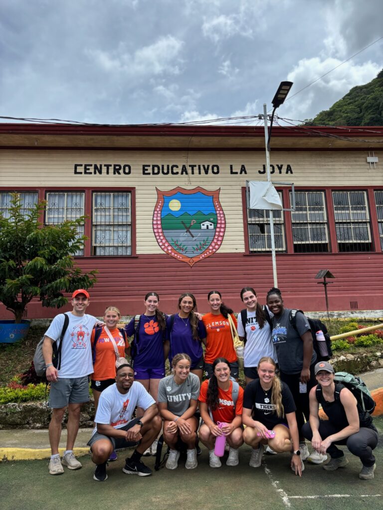 The team standing in front of the school they worked at throughout their trip