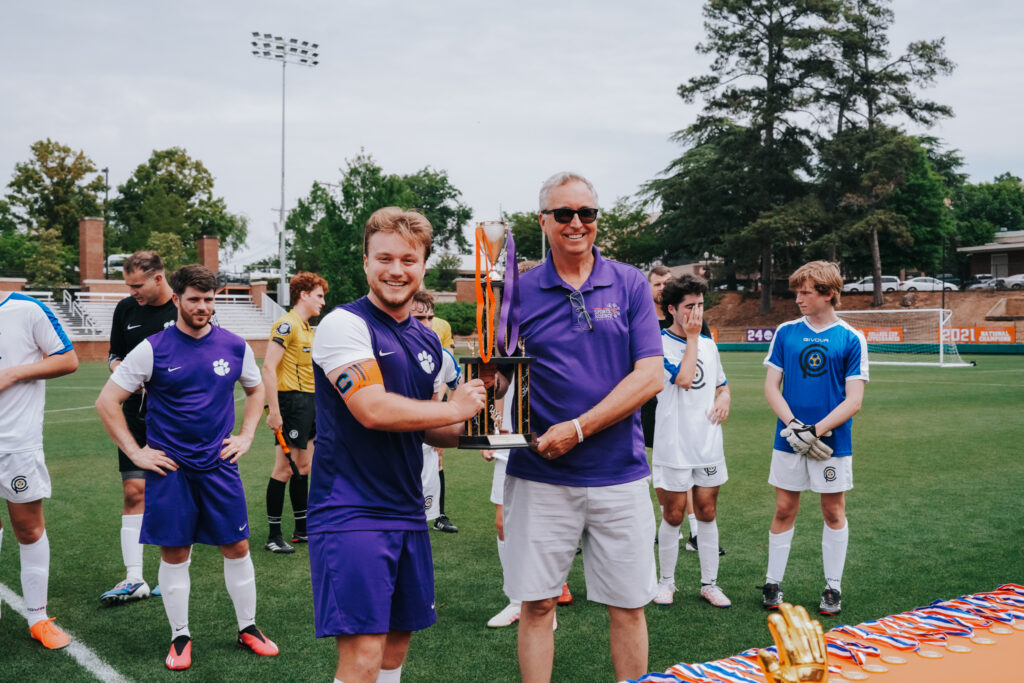 Two men hold up a large trophy