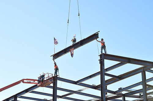 Construction workers hoist final steel beam into place.