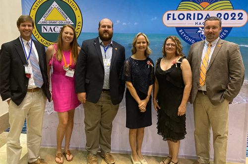 Group of Extension Agents in front of a banner.
