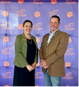 A man and a woman standing in front of a banner.