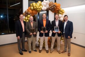 Five men standing with award plaques.