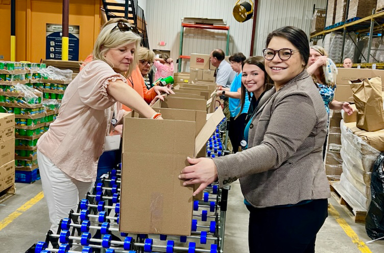 Several women packing boxes with food.