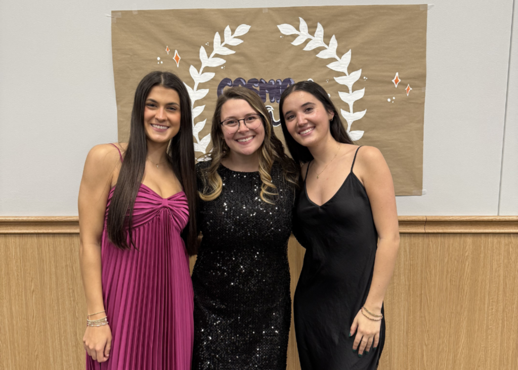 three girls smiling dressed up like at a dance. 