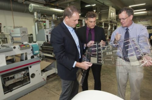 Charles ‘Chip’ Tonkin (left), Steve Foulger and Liam O’Hara, examine flexible hybrid electronics produced on a Clemson press.