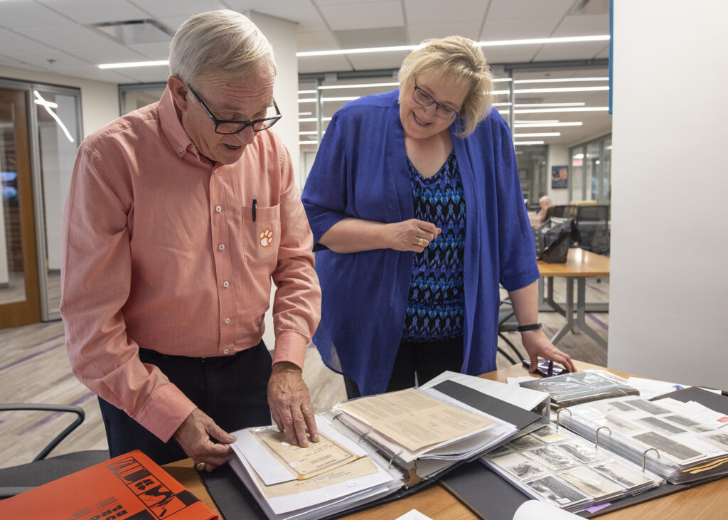 Bill Cline and Brenda book look at a binder full of historical documents.
