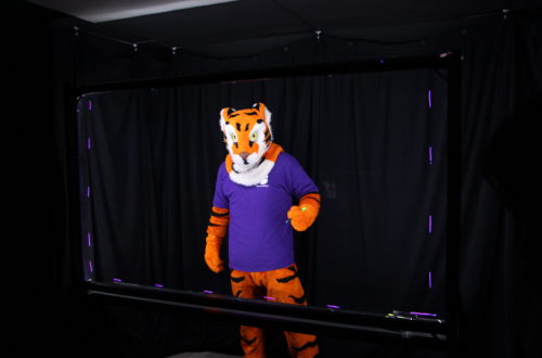 Clemson Tiger mascot holding a marker behind the Lightboard.