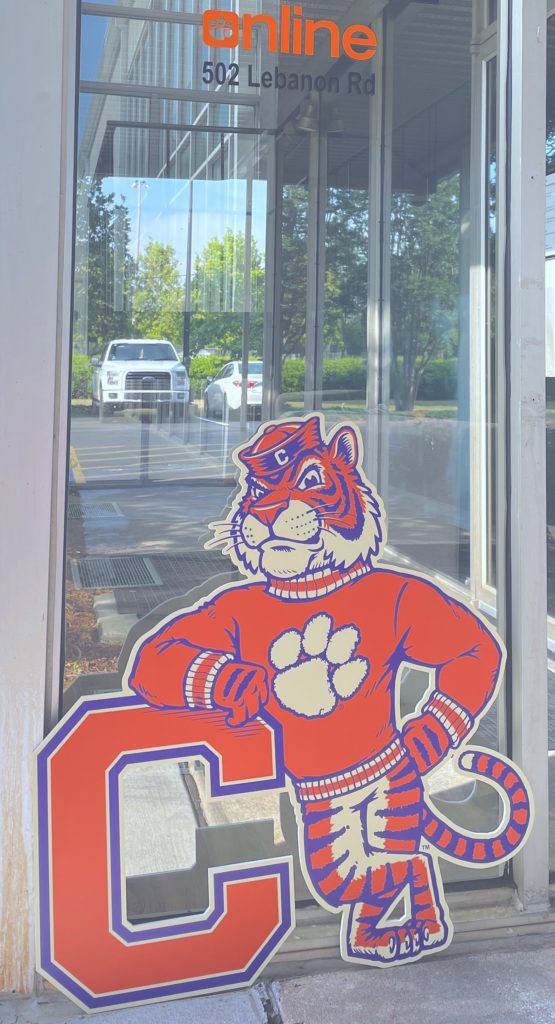 A foam cutout of a vintage Tiger mascot propped up against the Clemson Online door.