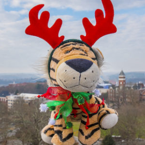Stuffed tiger wearing red reindeer antlers with campus views in the background.