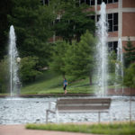 Woman walking around reflection pool at Cooper Library on campus