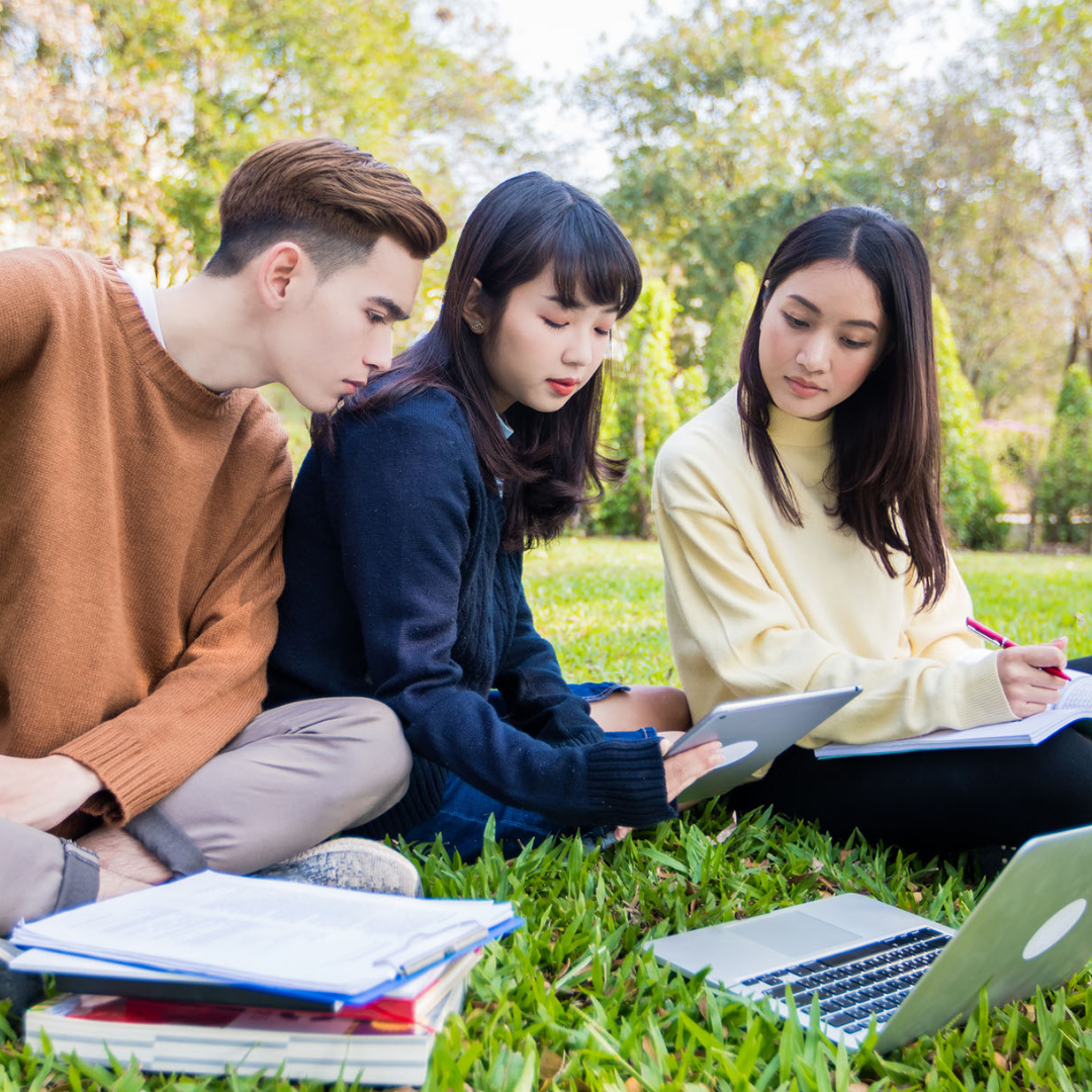 Students looking at computers while sitting outside