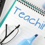 A blue highlighter sitting next to glasses has written "Teaching" on a notepad