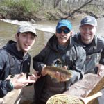 Fly fishing instructor Mike Watts celebrating a catch with two of his former students.