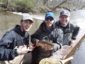 Fly fishing instructor Mike Watts celebrating a catch with two of his former students. 