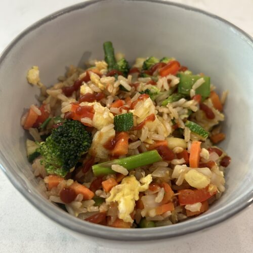 Asian style fried rice with brown rice, broccoli, carrots, zucchini, asparagus, onion, ginger, snow peas, and garlic