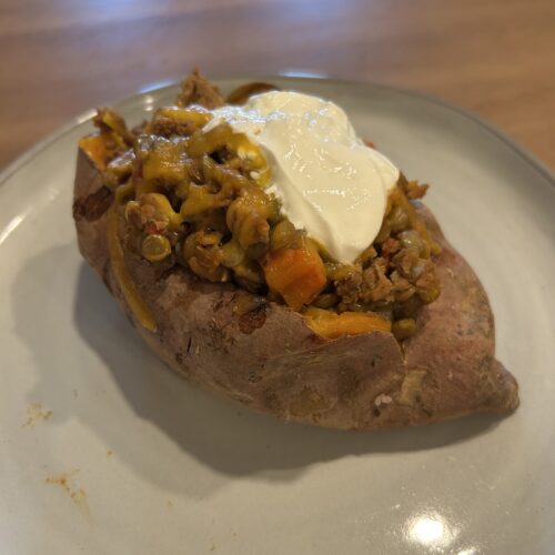 baked sweet potato topped with turkey lentil chili, cheese, and sour cream