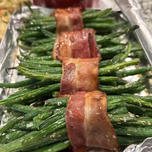 Green bean bundles wrapped in bacon and topped with brown sugar on a sheet pan