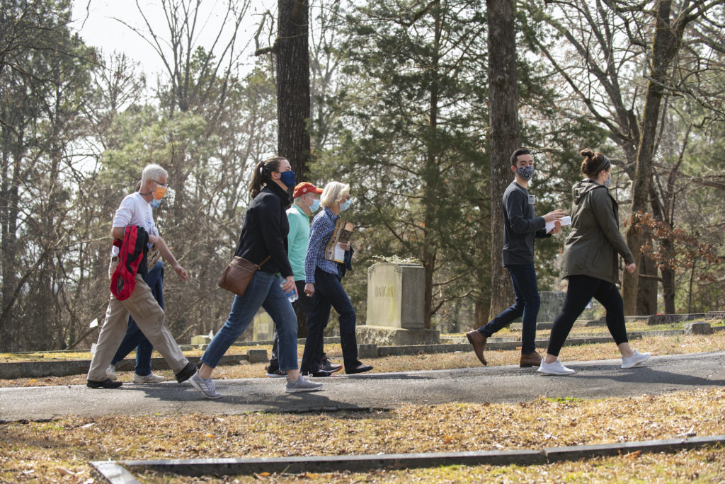 Visitors and student hosts walk along a path in the African American Burial Ground in Woodland Cemetery.