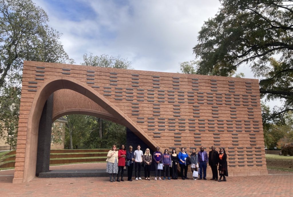 The cemetery team and Lemon Project team stand together in front of the Hearth Memorial at William & Mary in Virginia.